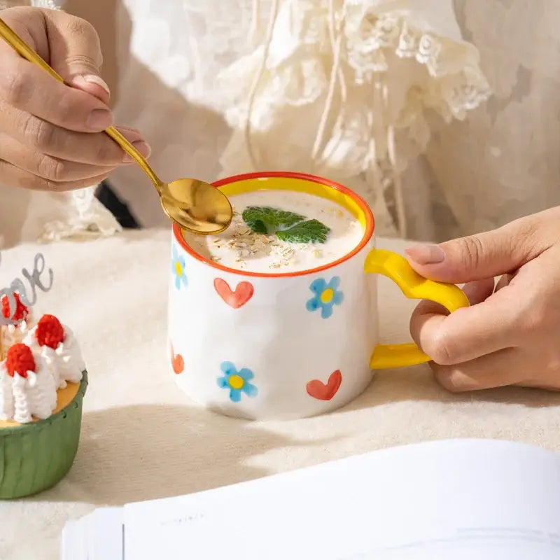 White ceramic mug with yellow handle and rim decorated with blue flowers and red hearts decorbites love heart ceramic mug