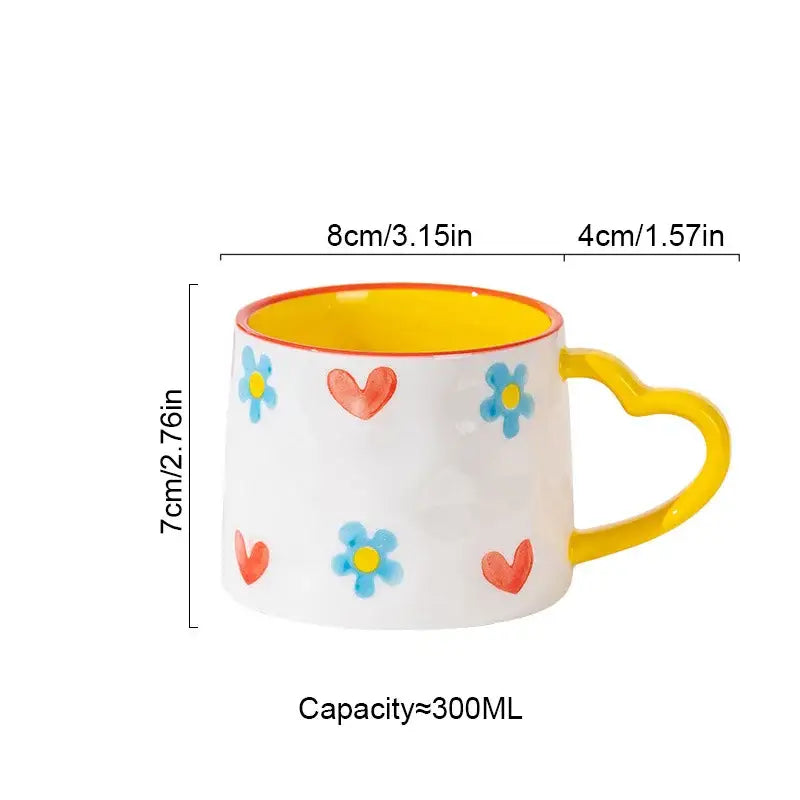 White ceramic mug with yellow interior and heart-shaped handle featuring hand-painted blue flowers and red hearts decorbites love heart ceramic mug