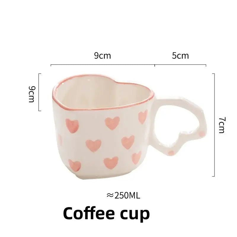 A white ceramic coffee cup with pink love heart hand painted decals and a matching heart shaped handle by decorbites love heart