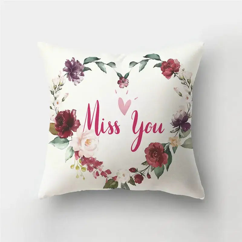 White throw pillow cover with pink red purple floral wreath and miss you text featured in DecorBites love heart print pillow
