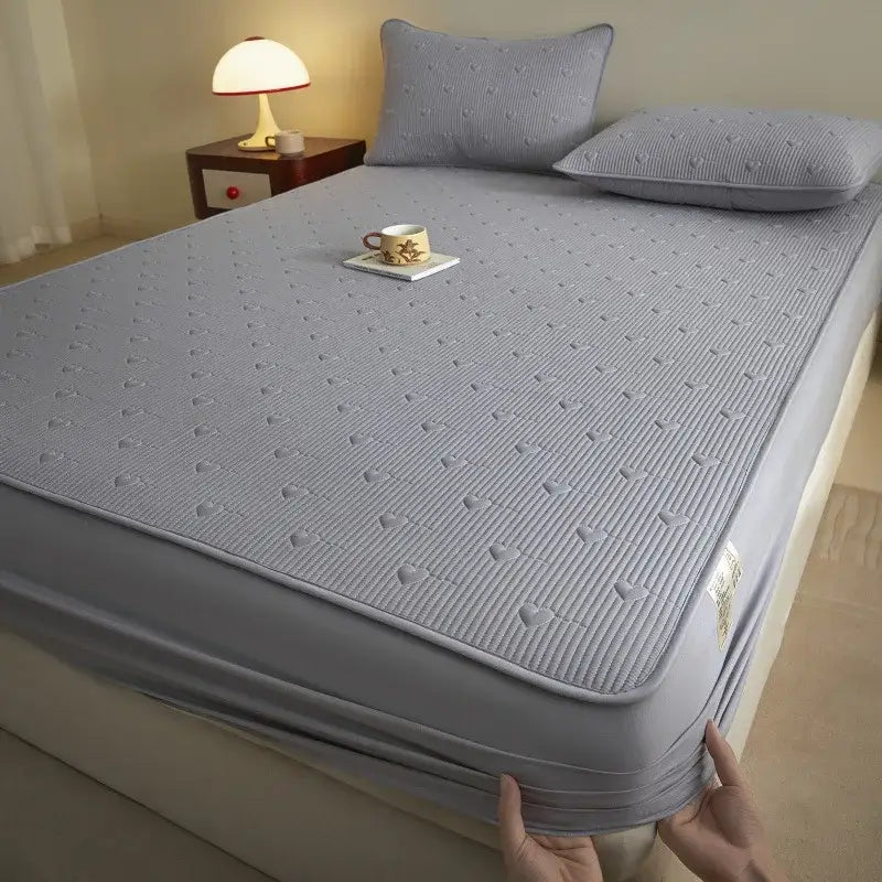 Gray quilted mattress protector with subtle heart pattern and elastic edge, complementing decorbites love pattern fitted sheet