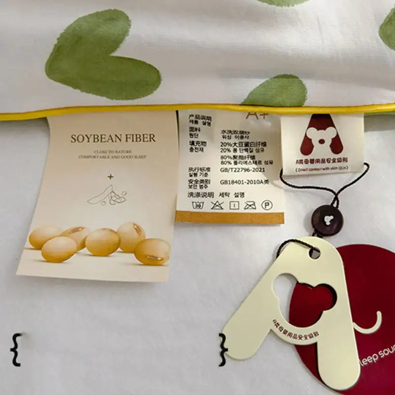 A cream-colored elephant-shaped tag with red heart cutout and black string on decorbites love print soft summer quilt