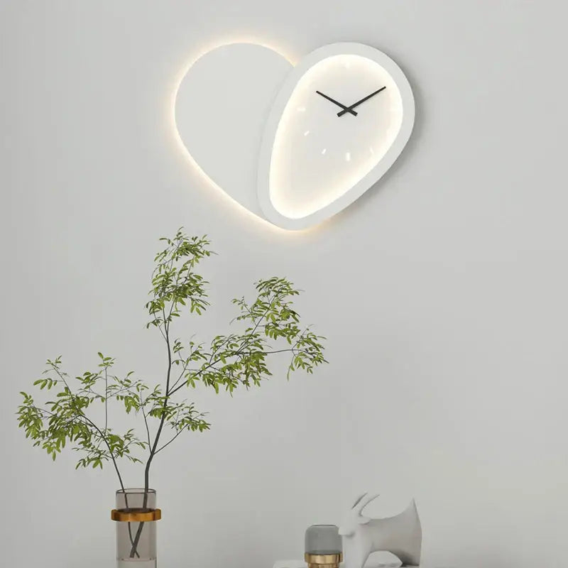 A modern white decorbites love shaped wall lamp with dimmable led light and minimalist black hands clock