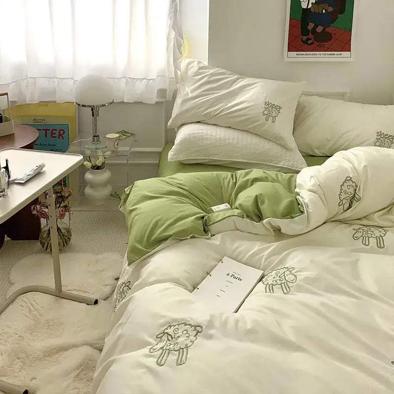 White DecorBites™ bedding set with sheep embroidered design in sage green and cream featuring quilted texture