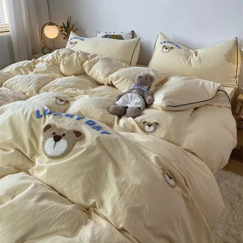 Cream-colored plush teddy bear and sheep embroidered bedding set with lucky day text and matching pillowcases by DecorBites
