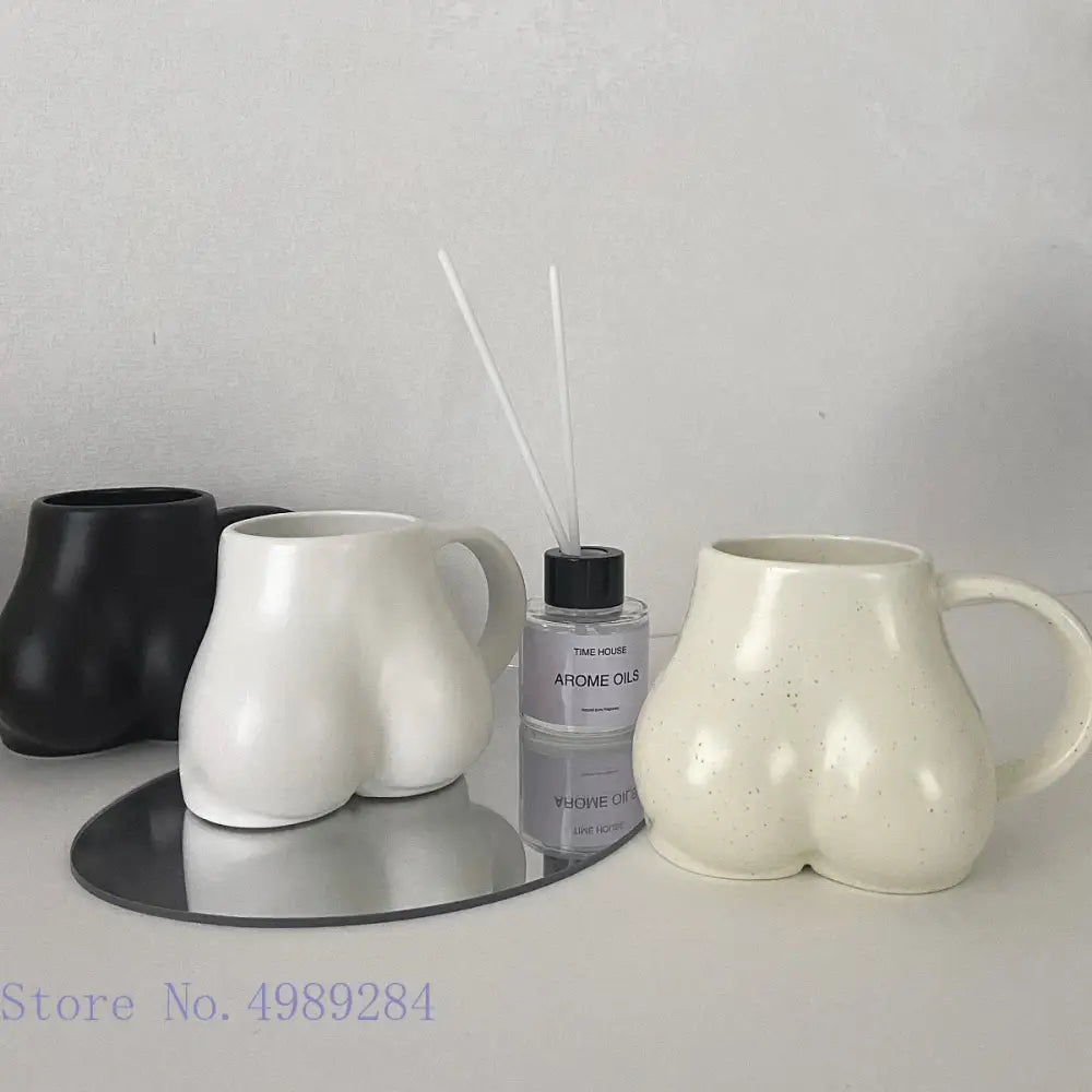 Cream-colored ceramic coffee cup with playful rounded buttocks shape and subtle speckled texture by DecorBites