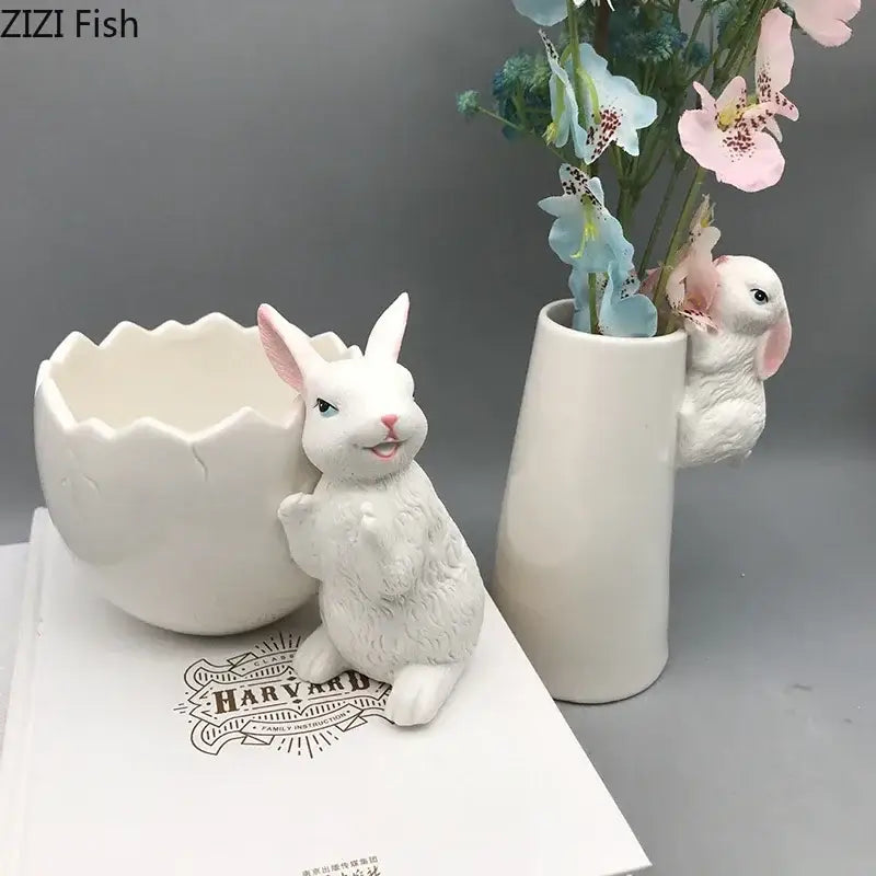 White ceramic figurine with textured fur and pink ears beside a cracked egg-shaped ceramic vase decorbites lovely rabbit