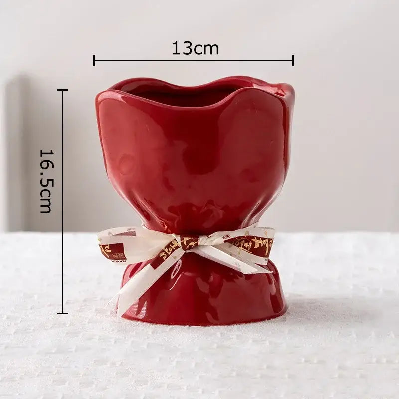 A glossy red ceramic vase shaped like a tulip from the decorbites lovely ribbon vase set with a white and gold ribbon