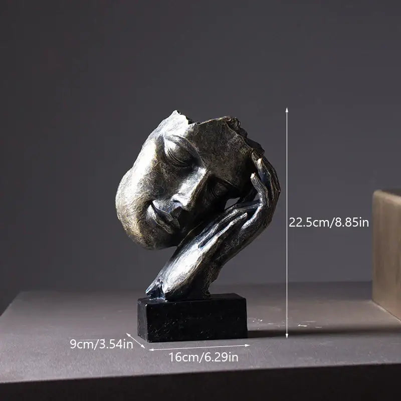 A metallic abstract face sculpture resting on its hand from DecorBites loving couple resin statue for interior decor