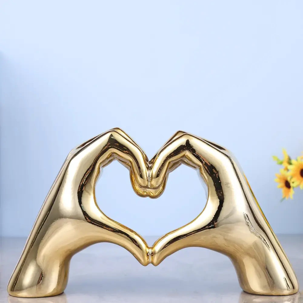 Golden glossy ceramic decorbites loving gesture heart sculpture of two hands forming a loving gesture heart shape