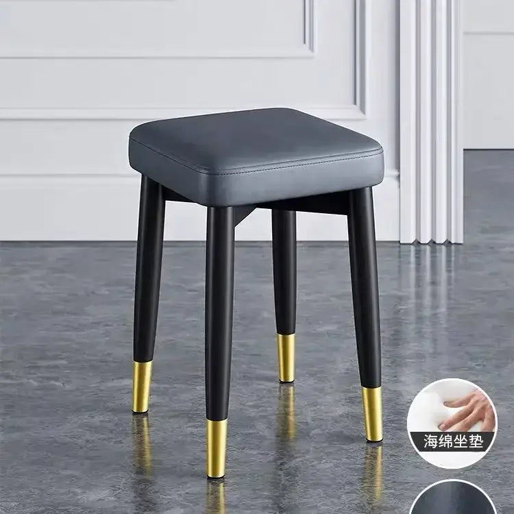 Gray upholstered decorbites low square stool bench with black legs and gold-tipped feet for dining and kitchen use