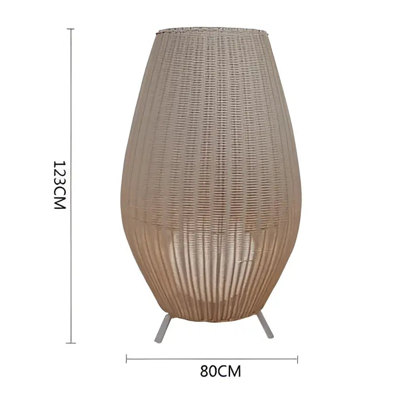 Beige woven rattan floor lamp with tapered vase shape and three metal legs decorbites lucide colin rattan design