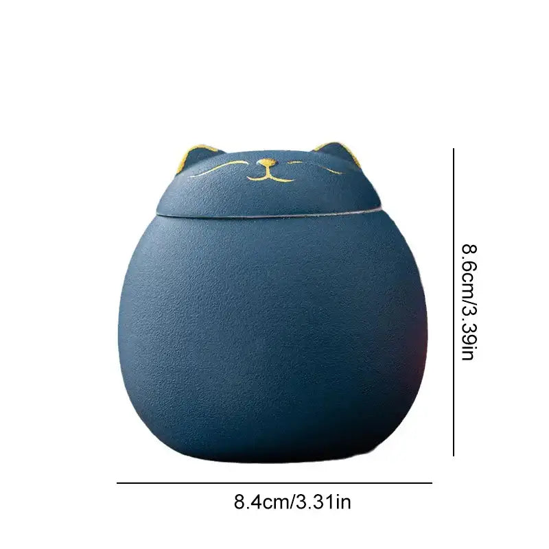 A navy blue ceramic cat-shaped DecorBites lucky cat tea storage jar with gold-trimmed ears for tea storage