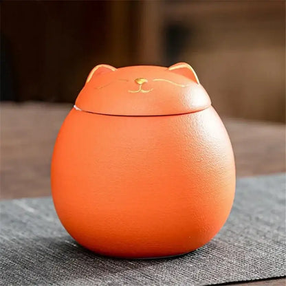 Orange ceramic tea storage jar shaped like a smiling cat with gold accents for household tea and candy storage