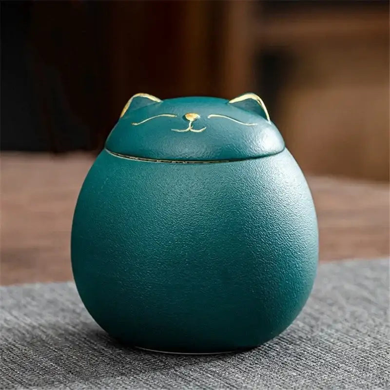 Teal ceramic cat-shaped tea storage jar with gold-trimmed ears and facial details for household tea and candy storage