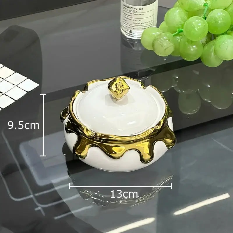 White ceramic ashtray with gold metallic accents and lid featuring a golden cube knob from DecorBites lucky ceramic