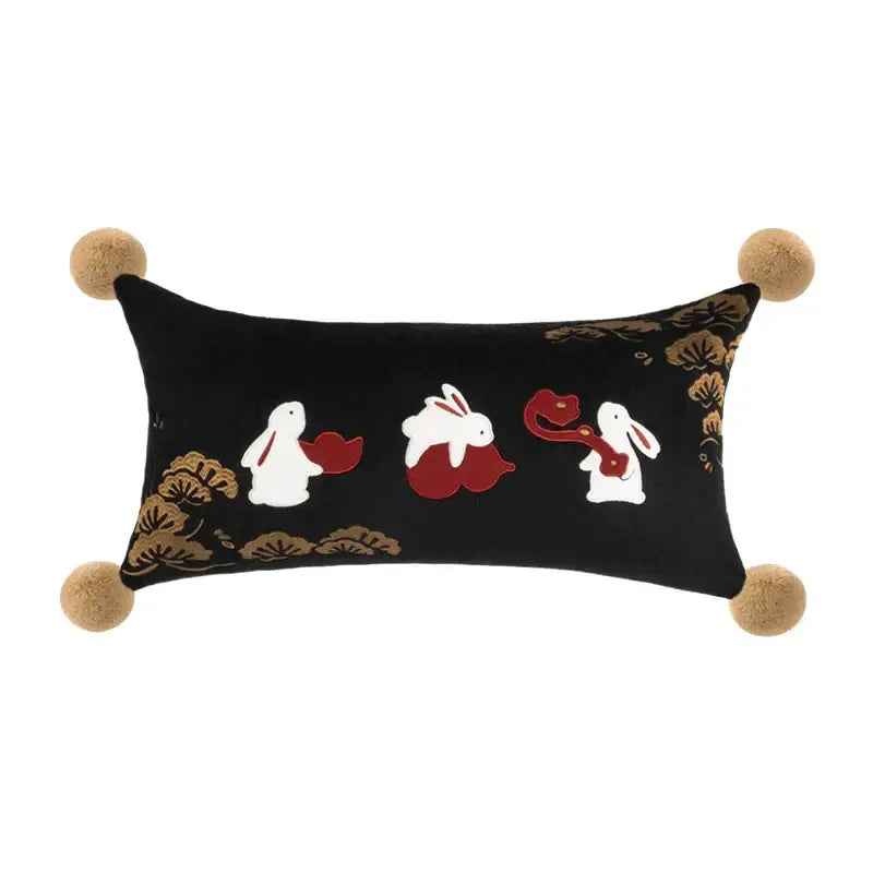 Black velvet rectangular pillow with white embroidered rabbits holding red fans gold leaf patterns and tan pom-poms by decorbites lucky rabbit pine forests