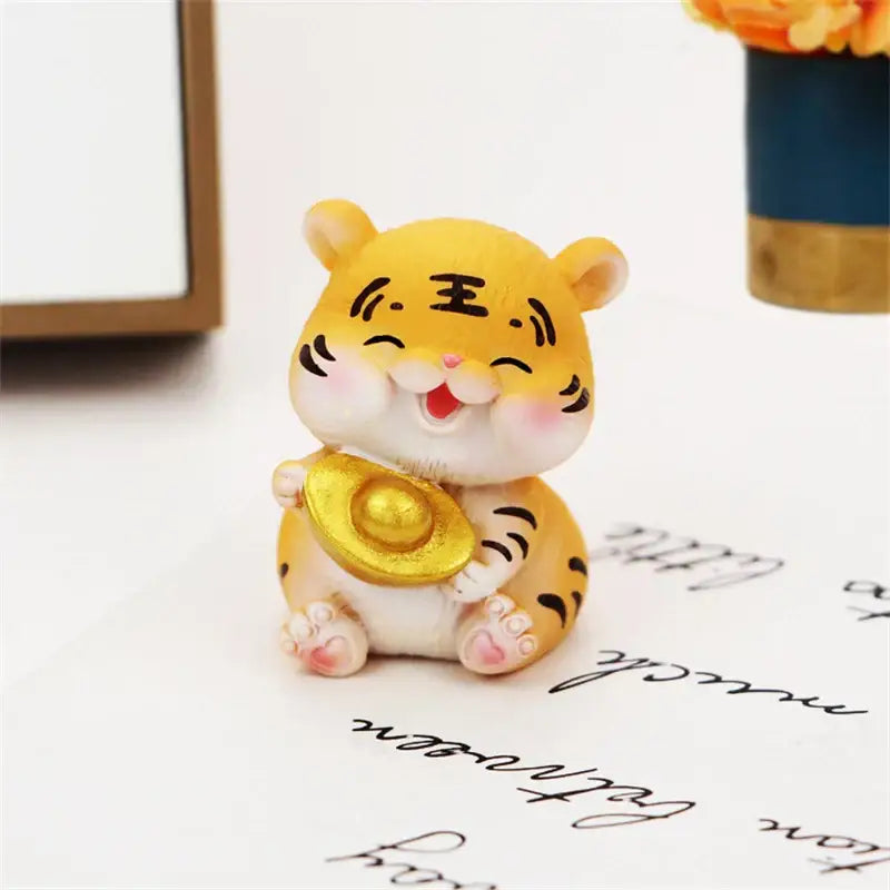 DecorBites™ lucky tiger figurine in yellow with black stripes holding a golden ingot for new year fortune decor