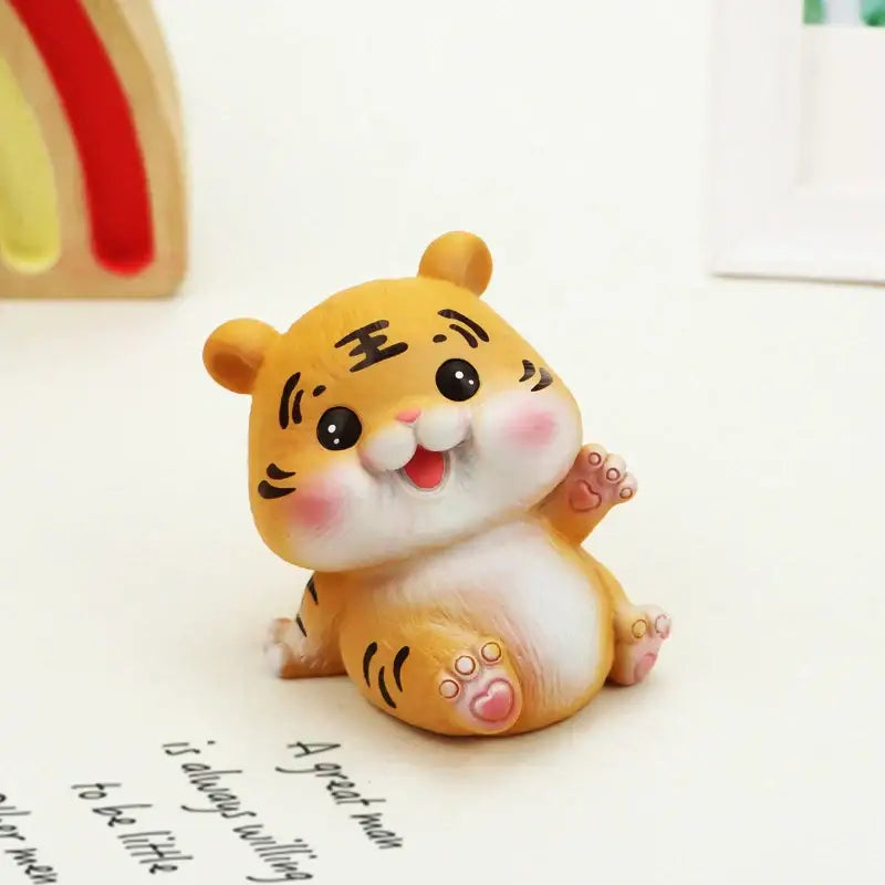Adorable orange lucky tiger figurine with black stripes and pink cheeks sitting on a white surface for home decor