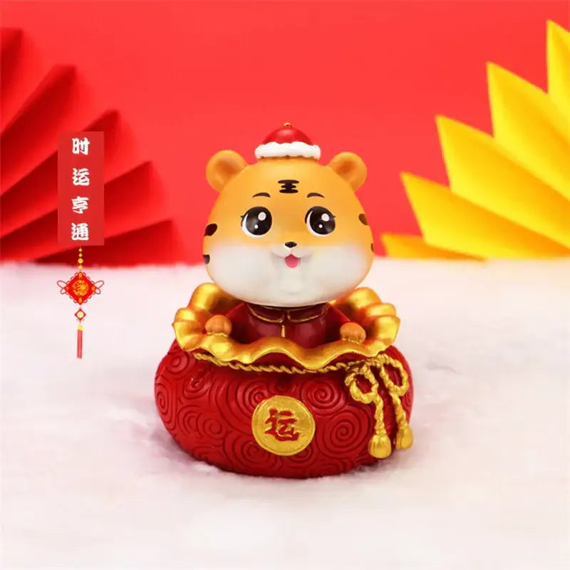 DecorBites lucky tiger figurine in orange wearing santa hat and traditional Chinese attire on red money bag with 运 character