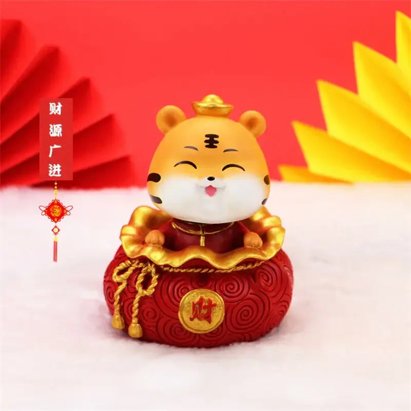 A cheerful golden lucky tiger figurine in a red robe sitting on a decorative red money bag for home decor