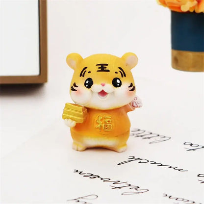 A cheerful yellow lucky tiger figurine holding golden bars in an orange outfit with chinese characters for new year decor