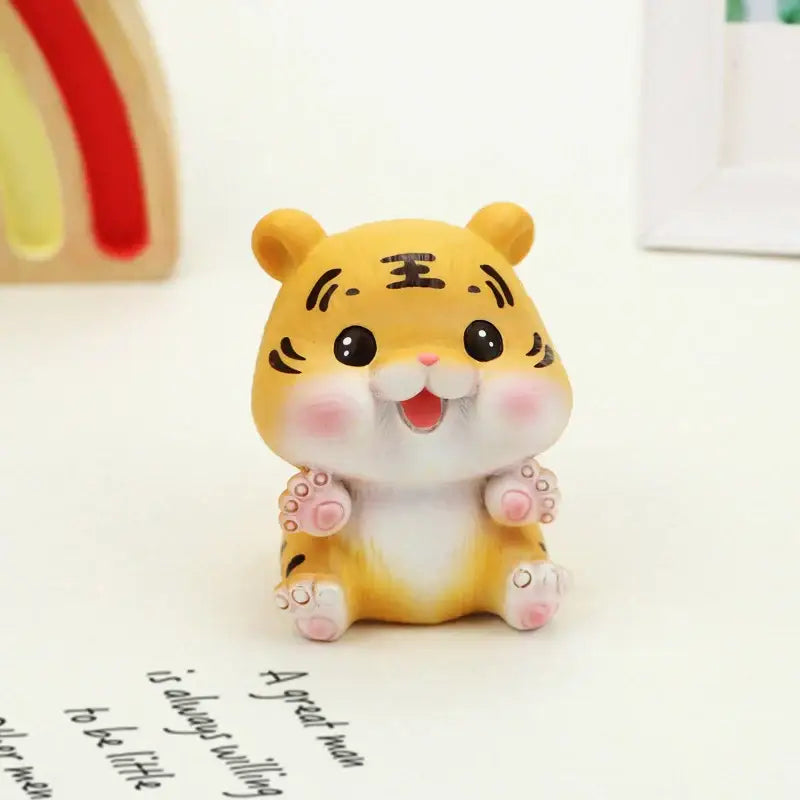 Decorbites™ lucky tiger figurine in yellow with black whisker markings and pink cheeks sitting on a white surface