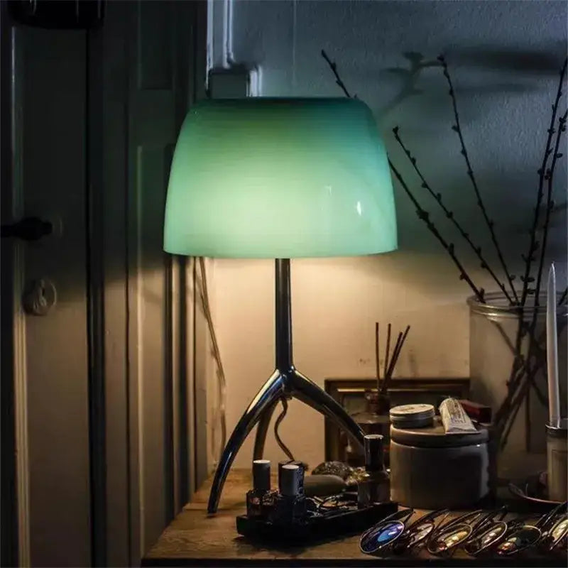 A sleek DecorBites Lumiere Piccola chrome table lamp with a translucent green glass shade and polished tripod base