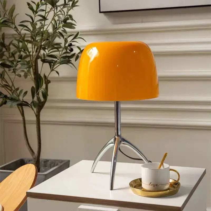 Vibrant orange glossy ceramic decorbites lumiere table lamp with sleek chrome tripod base for modern bedroom use