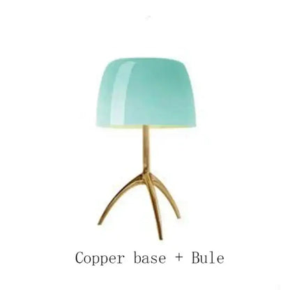 A decorbites lumiere table lamp with a translucent teal glass shade and polished copper tripod base for modern use