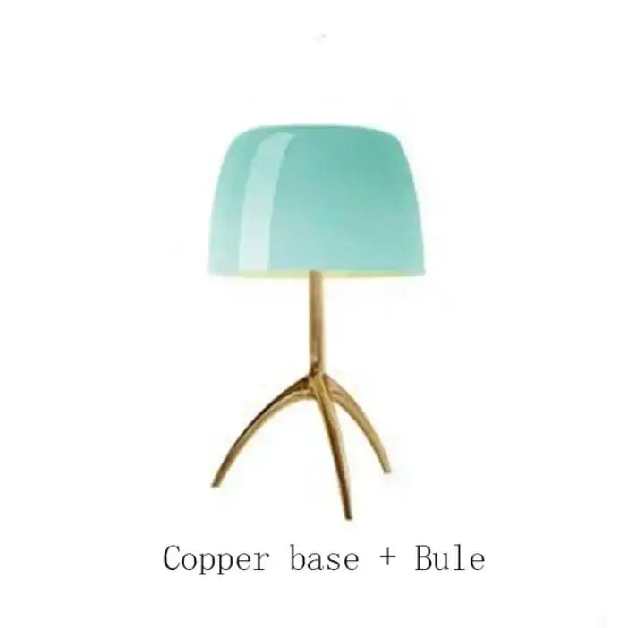A decorbites lumiere table lamp with a translucent teal glass shade and polished copper tripod base for modern use