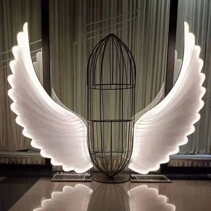 A glowing white led angel wings sculpture with a black wire cage body by decorbites luminescent angel wings lamp