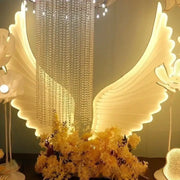 Illuminated white angel wings with a cascading crystal chandelier in the decorbites luminescent angel wings lamp for parties