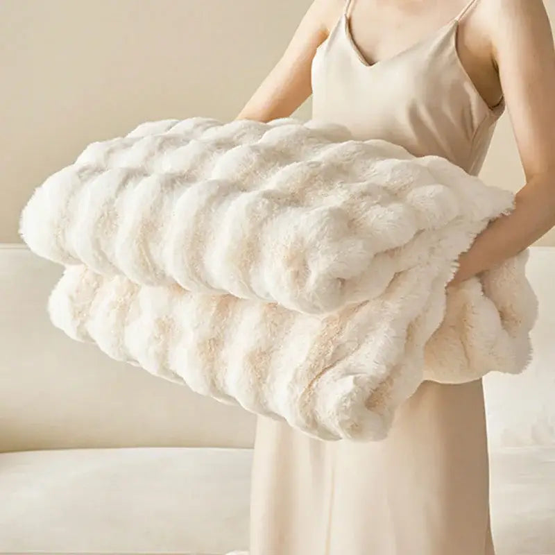 A plush off-white decorbites luxe faux rabbit fur throw blanket with soft textured surface and rolled edges for cozy use