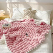 Pink chunky knit throw blanket with white pom-pom trim and faux rabbit fur texture for cozy bed warmth by DecorBites™