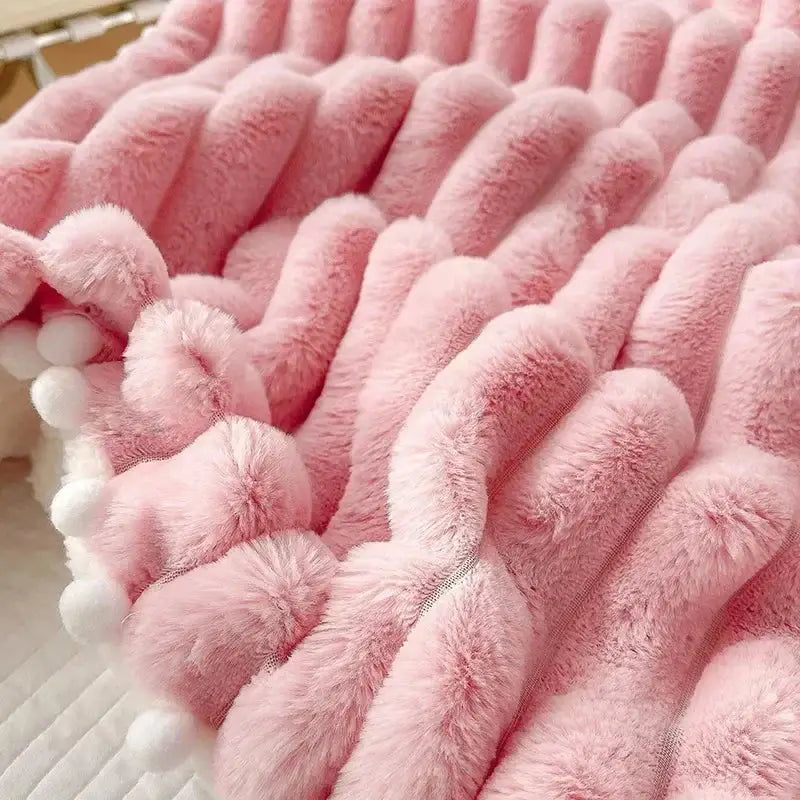 Pink plush faux rabbit fur weighted double blanket with ribbed texture and white pom-poms for cozy bed warmth