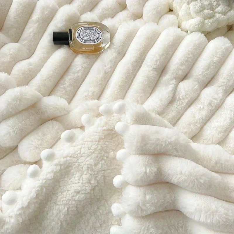 White fluffy pom-pom blanket with black cap and silver logo on perfume bottle.