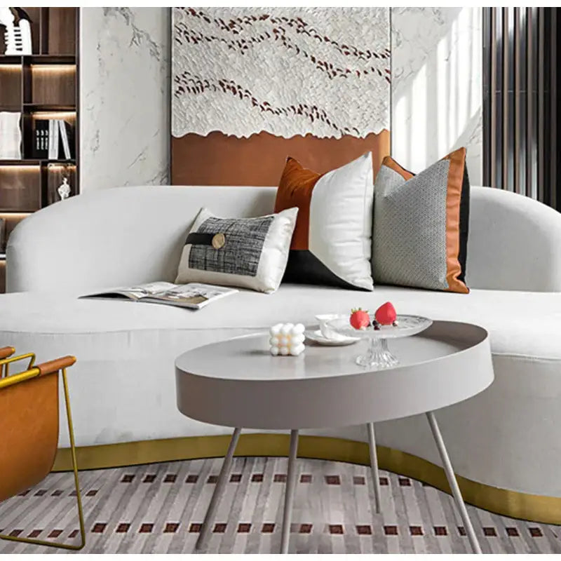 Modern oval coffee table with matte gray top and slender metallic legs pictured alongside decorbites luxe flannelette leather patchwork cushion covers