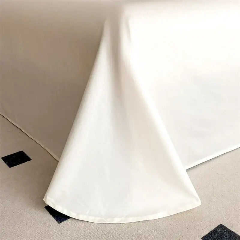 A crisp white bed skirt of smooth glossy fabric drapes mattress edge in decorbites luxe floral embroidery bedding set