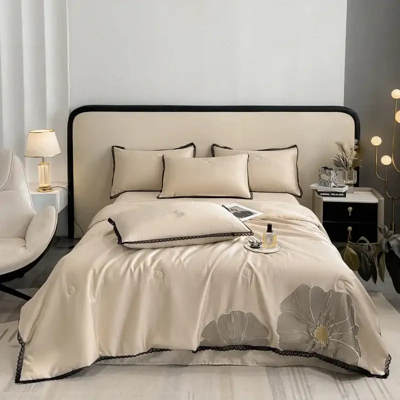 Cream-colored satin quilt set with luxe flower embroidered gray floral design and black lace trim by decorbites
