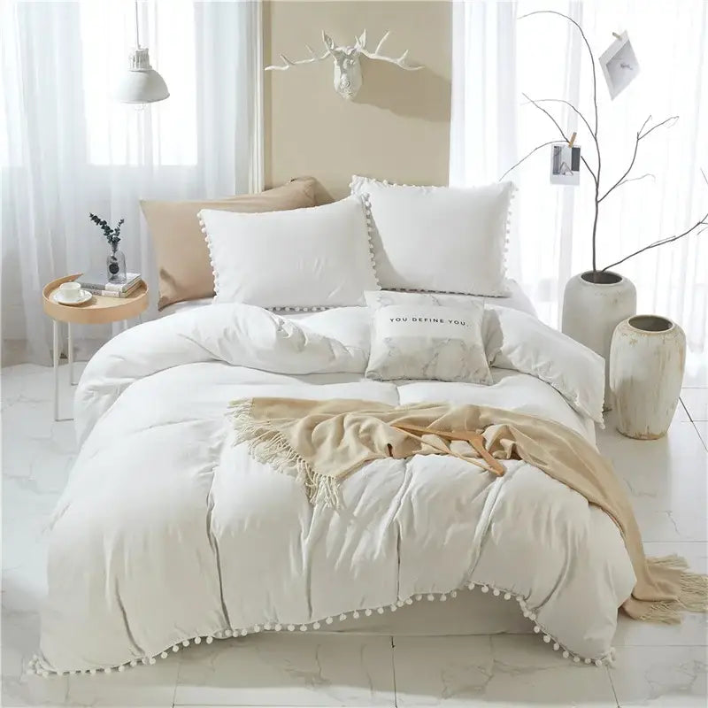 Cream-colored quilted duvet set with pom-pom trim and matching throw from decorbites luxe furball tasseled bedding set