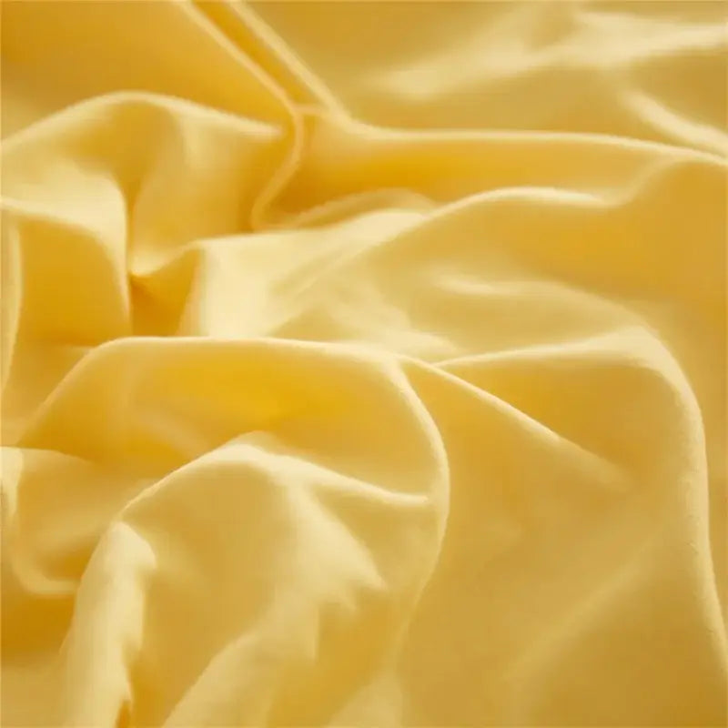 Soft pale yellow fabric with smooth glossy texture and folds in decorbites luxe furball tasseled bedding set
