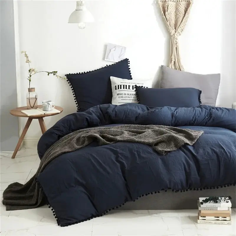 Navy blue quilted comforter with black pom-pom trim from DecorBites Luxe Furball tasseled bedding set queen king size