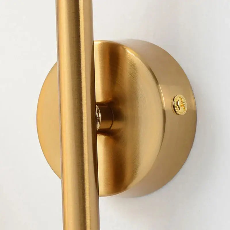 Gold-finished wall sconce with sleek cylindrical rod and circular base decorbites luxe glass ball for modern spaces