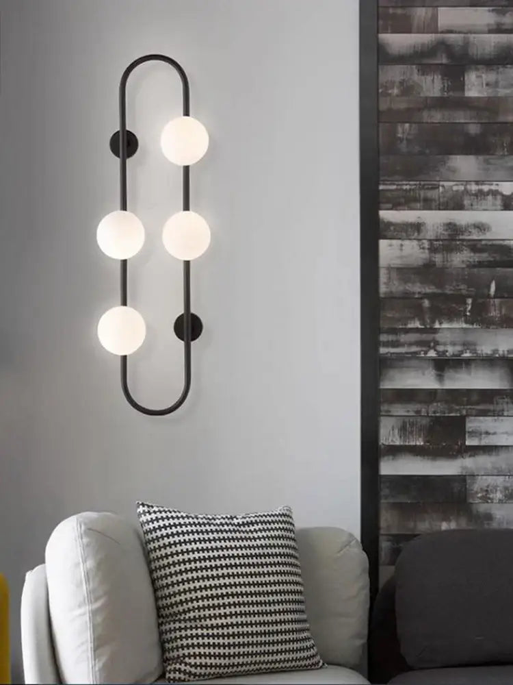 Black metal wall sconce with five frosted globe bulbs in a curved design for modern bedroom by decorbites luxe glass