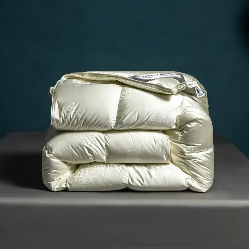 Cream-colored satin-finish quilt with subtle floral embroidery and puffy design in decorbites luxe goose duck down quilt