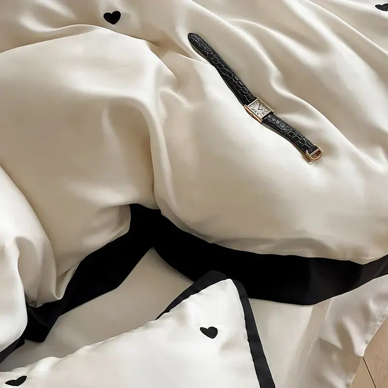 A sleek black crocodile-textured watch strap with gold-tone clasp rests on creamy white luxe heart embroidered bedding set