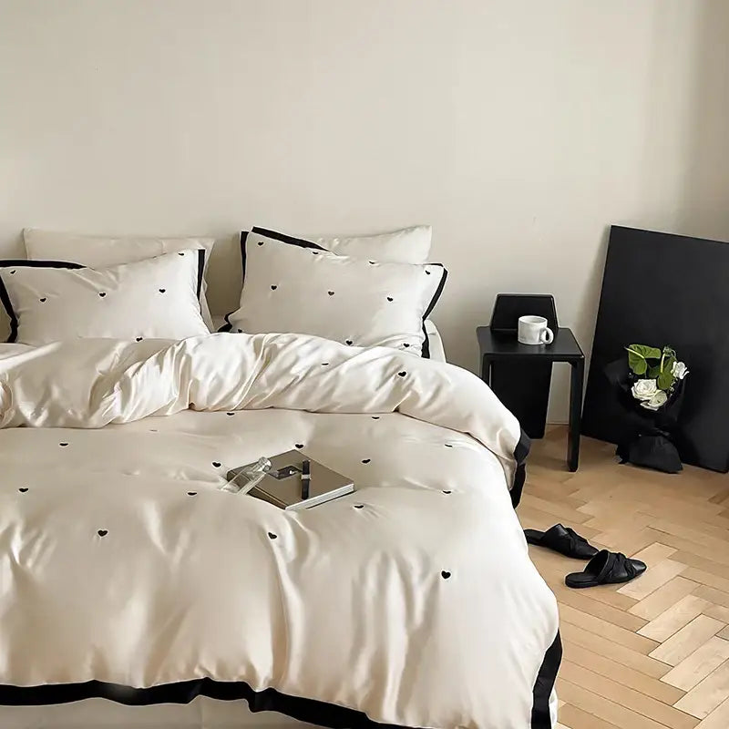 Cream-colored 100% lyocell bedding set with luxe heart embroidered design and black trim from DecorBites™