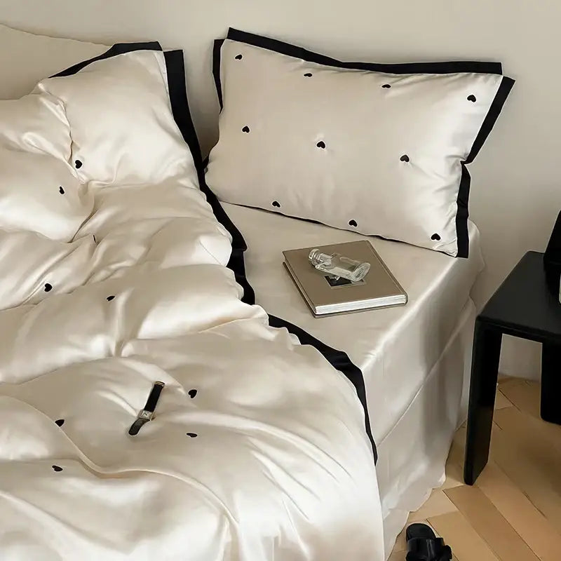 White satin bedding set with black trim and subtle heart embroidery from DecorBites™ luxe heart embroidered collection