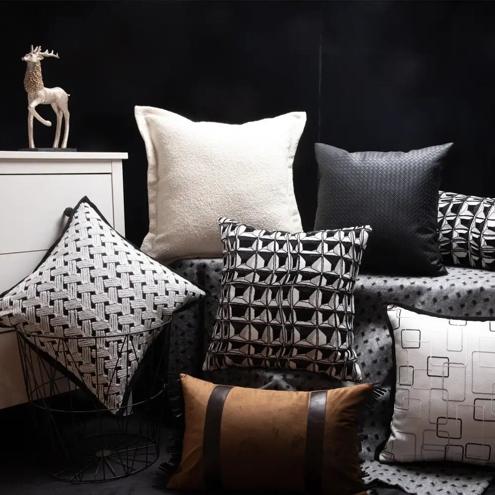 A collection of decorbites luxe hotel throw pillows in black white and brown with geometric patterns and textured fabrics